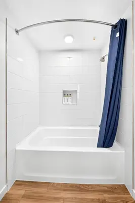 a bathtub in a bathroom with a blue shower curtain at fusion hollywood in Los Angeles