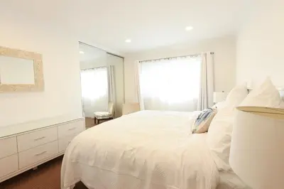 a white bedroom with a bed and a large mirror at SM ocean view in Los Angeles