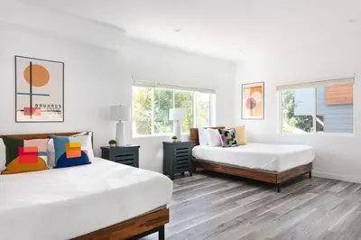 a white bedroom with two beds and a window at Prestige 5BR Townhome Near LA Hot Spots in Los Angeles