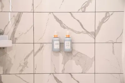 two bottles ofodorizers on a white tiled bathroom wall at Elevated Escape Luxury 1BR in Hollywood in Los Angeles