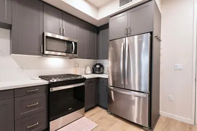 a kitchen with black cabinets and a stainless steel refrigerator at Elevated Escape Luxury 1BR in Hollywood in Los Angeles