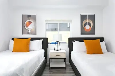 two beds with orange pillows in a bedroom at Upscale LA Getaway Sleeps 8 with Free Parking in Los Angeles