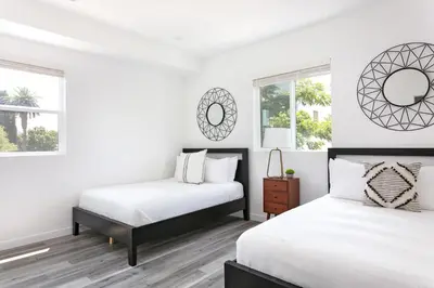 two beds in a bedroom with white walls and windows at Central 4BR Townhome Modern Perks in Los Angeles