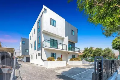 a white building with a fence in front of it at 3BR Urban Retreat with Modern Amenities in Los Angeles