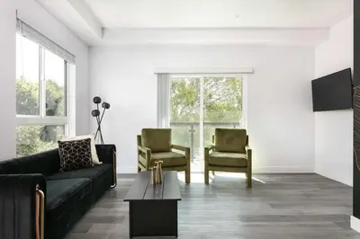 a living room with a black couch and two chairs at 3BR Urban Retreat with Modern Amenities in Los Angeles