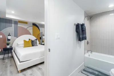 a bedroom with a white bed and a bath tub at Sunset Views from Private Rooftop in Luxe Townhome in Los Angeles