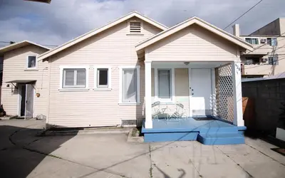 a white house with a porch with a chair on it at Cozy room in East Holywood, 7 min from holllywood, 15 from downtown, 20 to hollywood sing in Los Angeles
