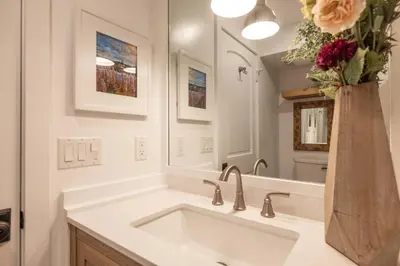 a white bathroom with a sink and a vase of flowers at Cove Lakeside Jacuzzi, Central AC, Stunning View in Big Bear Lake