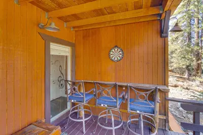a porch with blue chairs and a clock on a house at Golf and Swim! Pine Mtn Club Retreat with Game Area in Pine Mountain Club
