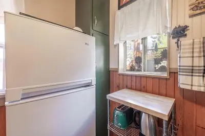 a refrigerator in a kitchen with a table next to a window at Dream Lake Cabin Spa, EV Charger, Gated, by lake! in Big Bear Lake
