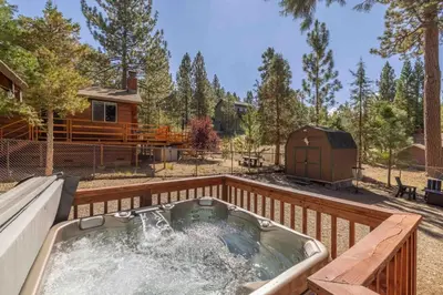 a hot tub on a deck next to a cabin at Dream Lake Cabin Spa, EV Charger, Gated, by lake! in Big Bear Lake