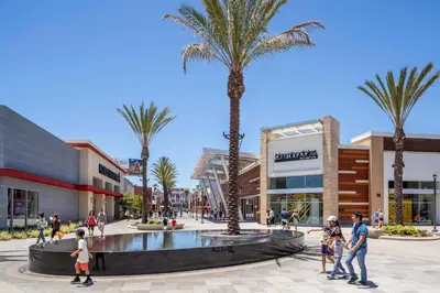 people walking in a shopping mall with palm trees at Resort-Style APT with Pool, Gym & Parking 10min to Disneyland in Santa Ana