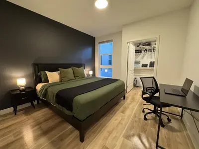 a bedroom with a bed and a desk and a laptop at Luxe Deco Haven with Pool, Gym & Parking Close to Disneyland in Santa Ana