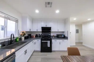 a kitchen with white cabinets and a black appliances at Modern Luxe Ensuite by USC Shared Living in Los Angeles