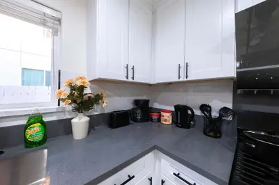 a kitchen with white cabinets and a counter with flowers at Modern Private Room in Shared Home -Walk to USC in Los Angeles