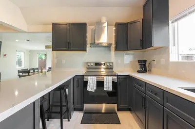 a kitchen with black cabinets and a stove top oven at Spacious 5 BR Brand New House LAX in Inglewood