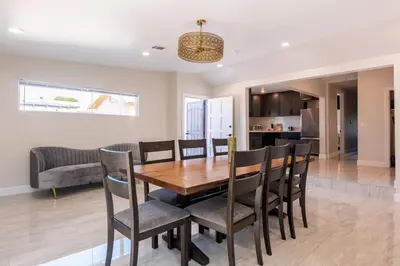 a dining room and kitchen with a wooden table and chairs at Spacious 5 BR Brand New House LAX in Inglewood