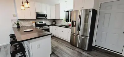 a kitchen with white cabinets and a stainless steel refrigerator at Cozy Home Away From Home in Northridge Hospital Heliport