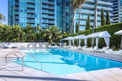 a swimming pool with chairs and umbrellas in a resort at Platinum Suites - Gym & Pool & Hot Tub & BBQ in Los Angeles