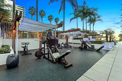 a row of exercise equipment in a gym with palm trees at Platinum Suites - Gym & Pool & Hot Tub & BBQ in Los Angeles