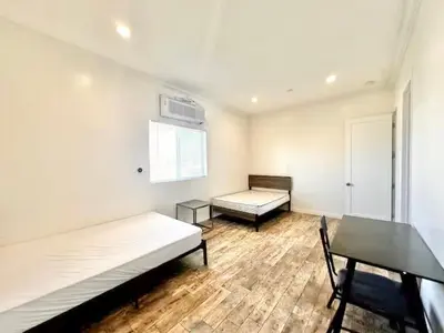 a room with two beds and a table and a window at Lovely 3-bedroom house with AC in vibrant Los Angeles Near USC in Los Angeles