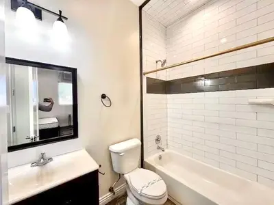 a bathroom with a sink and a toilet and a mirror at Lovely 3-bedroom house with AC in vibrant Los Angeles Near USC in Los Angeles