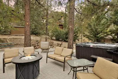 a patio with chairs and a fire pit and trees at Lakeview Pines Log Cabin - Custom Built Village Log Cabin Retreat w/ Hot Tub, Pool Table in Big Bear Lake
