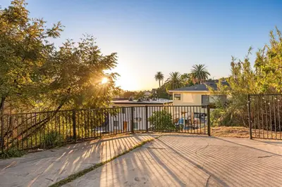 a gate in a driveway with trees and a house at Echo Park Spacious Two-Bedroom Apartment with Private Yard and Parking in Los Angeles