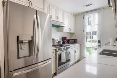 a white kitchen with a stainless steel refrigerator at Newly Built Pasadena Retreat Parking Great Location in Pasadena