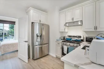 a kitchen with white cabinets and a stainless steel refrigerator at Stylish Pasadena Stay Near Old Town & Rose Bowl in Pasadena