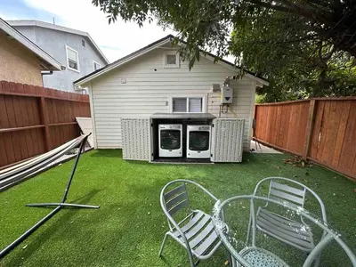 a yard with two chairs and a house at Modern Private Guesthouse with Parking, Yard, and Washer Dryer in Inglewood