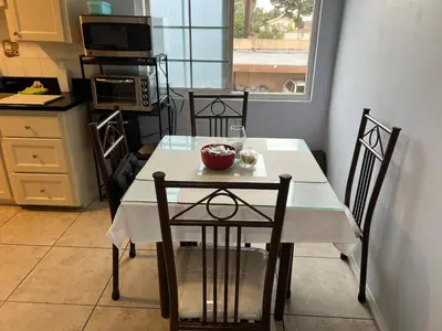 a kitchen with a white table and chairs and a microwave at 9621 San Juan - South Gate CA - Quick Drive to Hollywood & Beaches in South Gate