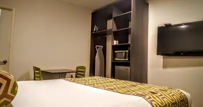a hotel room with a bed and a flat screen tv at Jewel City Inn in Glendale