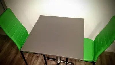 a table and two green chairs next to a wall at Jewel City Inn in Glendale