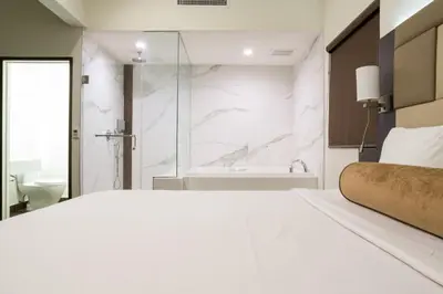 a white bedroom with a shower and a bed at Hotel Xilo Glendale in Glendale