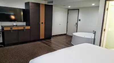 a room with a bed and a tv and a bathroom at Hotel Xilo Glendale in Glendale