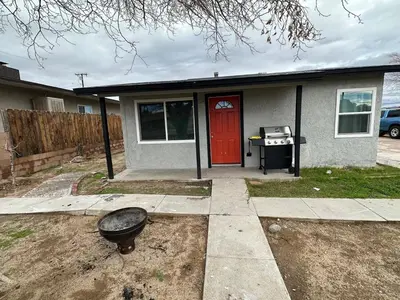 a house with a red door and a grill at Desert Oasis Retreat in Barstow in Barstow