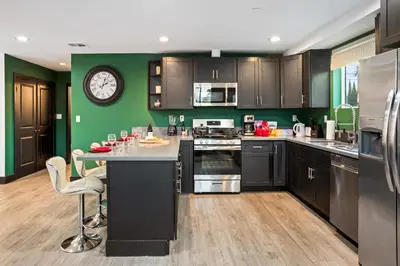 a kitchen with black cabinets and a clock on the wall at Spacious Luxury Villas in the heart of LA! Free parking and Jacuzzi in Los Angeles