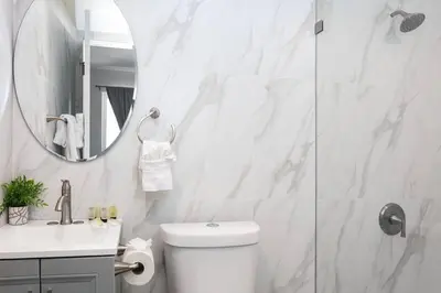 a white bathroom with a toilet and a mirror at Central 3BR Apt Near Americana in Glendale