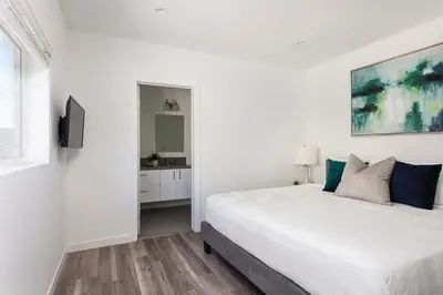a white bedroom with a large bed and a tv at Enjoy Stylish 4BR Townhouse Sleeps 8 with Wi-Fi in Los Angeles