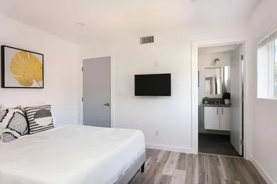 a white bedroom with a bed and a flat screen tv at Experience Luxury 4BR Townhouse Sleeps 8 with Parking in Los Angeles