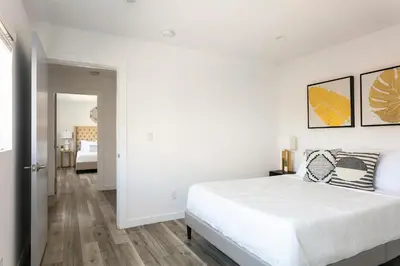 a white bedroom with a bed and a hallway at Experience Luxury 4BR Townhouse Sleeps 8 with Parking in Los Angeles
