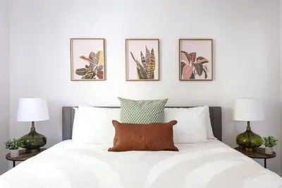 a bedroom with a white bed with four pictures on the wall at Luxury 2BR Apartment Great Area with Parking in Glendale