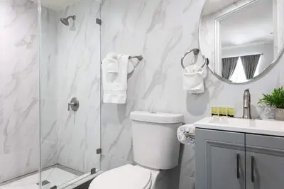 a bathroom with a toilet and a glass shower at Luxury 2BR Apartment Great Area with Parking in Glendale