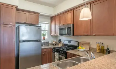 a kitchen with wooden cabinets and a stainless steel refrigerator at 1BR Luxury Apartment - Luxury Resort Amenities in Los Angeles