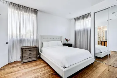 a white bedroom with a large bed and a mirror at Modern 4BR Villa Spacious Stylish In Prime Location in Los Angeles