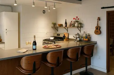 a kitchen with a counter with a stove and chairs at Ocean View Balcony, 4 Min Walk to Beach in Manhattan Beach