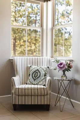 a room with a chair and a table with a vase of flowers at The Reel Deal, Luxury Family Cabin by Alpine Slide in Big Bear Lake