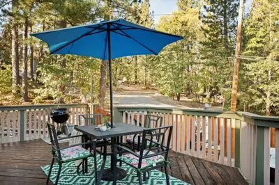 a table and chairs with an umbrella on a deck at Acorn Cottage in Big Bear Lake