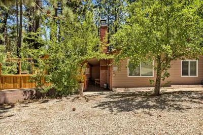 a house with a tree in front of a driveway at Lawliss Hideout in Big Bear Lake in Big Bear Lake